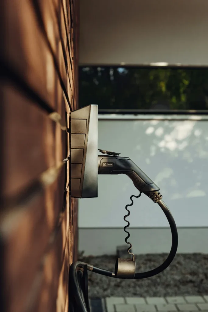 Ladestation mit angeschlossenem Elektroauto vor einem Wohnhaus – Elektrotechnik -Level Up