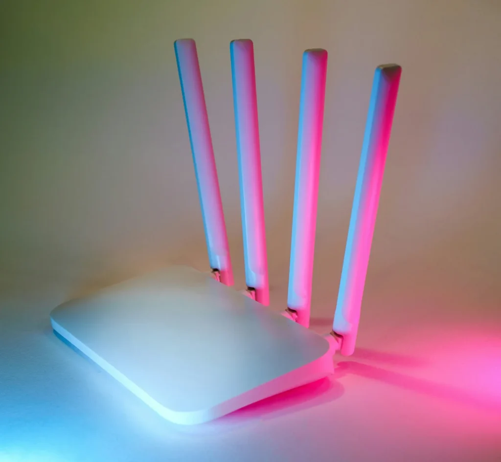Drei WLAN-Router mit leuchtenden LED-Antennen in Pink und Blau auf einem Tisch – Elektrotechnik -Level Up