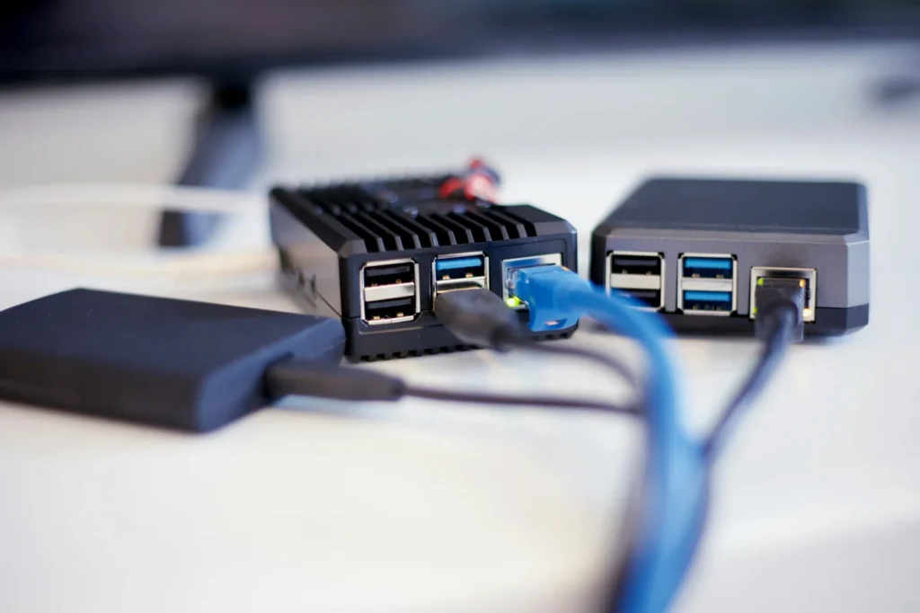 Nahaufnahme eines Mini-PCs oder Embedded-Systems mit angeschlossenen Netzwerkkabeln und USB-Verbindungen – Elektrotechnik -Level Up